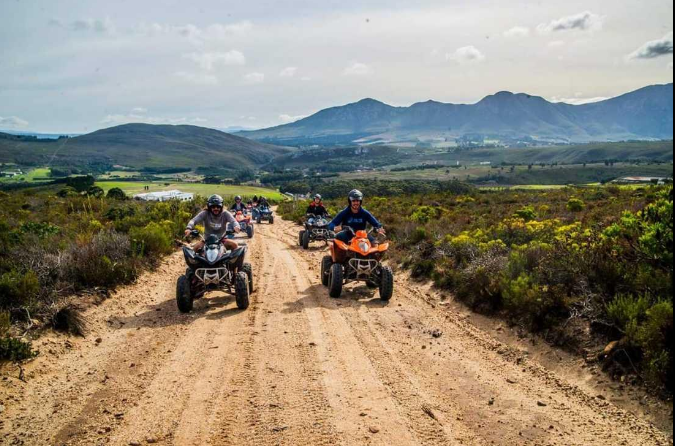 Travelers riding quad bikes across an adventurous outdoor trail.